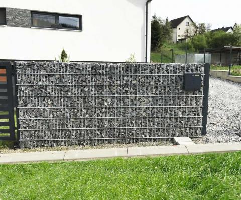 a dark gray gabion fence matched with the anthracite windows of the house