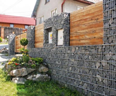 a gabion fence with a log and a niche for a meter