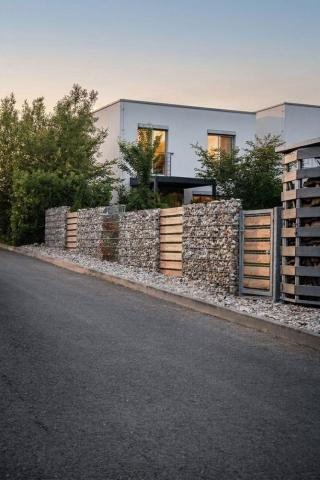 view of a gabion fence in front of a modern home